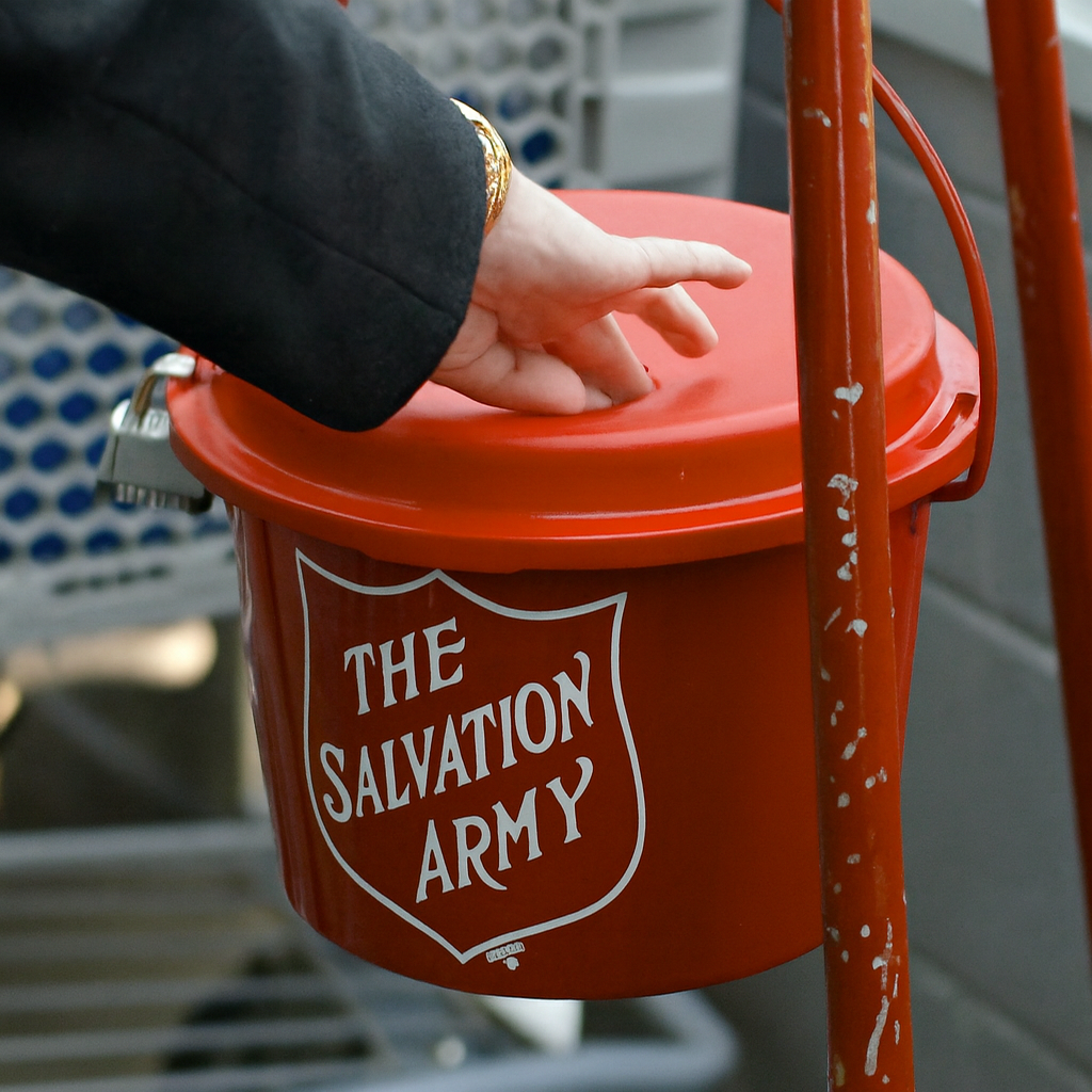Photo of a hand putting money into a Salvation Army red kettle